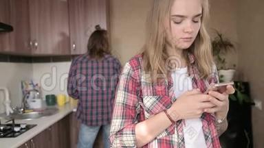 年轻的夫妻在厨房里。 一个有纹身的女孩在手机上给她的<strong>爱人</strong>写了一条信息