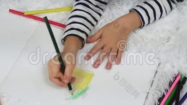 一个快乐的孩子躺在房子的地板上用铅笔画房子。 儿童的休闲.. 家庭和儿童