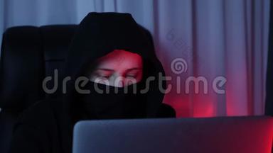 女人脸上戴着黑色面具和帽衫，看着电脑屏幕，打破密<strong>码</strong>。 年轻黑客破坏了<strong>我的</strong>安全保护