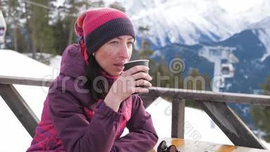 女人在山上的乡村木制露台上喝着温<strong>暖</strong>的<strong>茶</strong>。 女孩正在欣赏雪山的全景