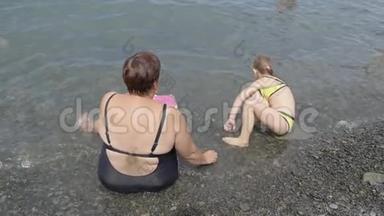 祖母带着一个<strong>小</strong>可爱的孙女在海里洗澡，家庭幸福。 祖母教的<strong>小东西</strong>
