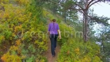 秋天，女孩爬上海岸陡坡上的小路