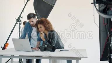 摄影师和模特在工作室里看笔记本电脑上的照片