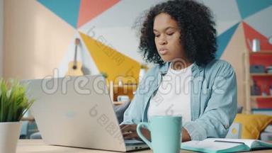 可爱的美国黑人妇女在家里用<strong>笔记本</strong>电脑写<strong>笔记本</strong>时动作缓慢
