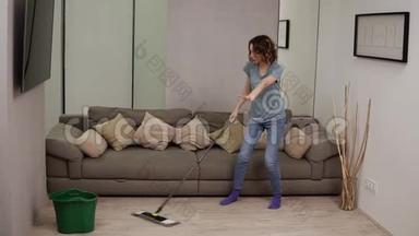 人，<strong>家务</strong>和<strong>家务</strong>观念-快乐的女人戴着耳机，拖把清洁地板，在家跳舞。 灰灰