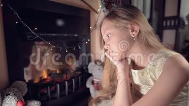 一个小<strong>悲伤</strong>失望的女孩坐在人造壁炉旁，在柔软的玩具旁边感到<strong>悲伤</strong>。 被宠坏的概念