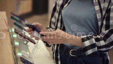 一个无法辨认的女人的腰部镜头`她的手在一家电子商店里选择了一部智能手机。 她把智能手机从