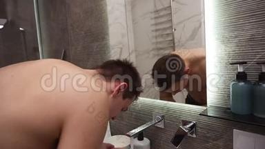 从水龙头里冒出来的冷水下，无顶的帅哥在水槽里洗脸。 每天早晨打扫卫生