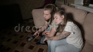 这对年轻夫妇正在看电视。女人<strong>切换</strong>频道，男人选择控制。