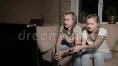 年轻夫妇正在看电视。 男人<strong>切换</strong>频道，女人选择控制。