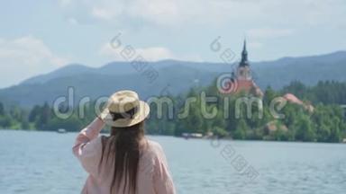 受启发的妇女在斯洛文尼亚的布莱德湖旁摊手