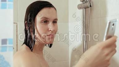 女孩洗澡用电话。 女人一边看社交网络的新闻，一边站在水流下