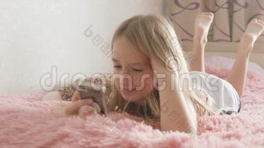 可爱的女孩在房间里躺在<strong>床上玩</strong>智能<strong>手机</strong>。