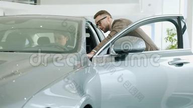 一位开朗的年轻女士在<strong>展厅</strong>检查汽车内部，与推销员交谈