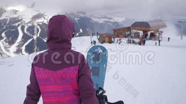 在滑雪场，女孩滑雪者手里拿着滑雪板。 雪山上的运动女人。 滑雪冬季阳光明媚