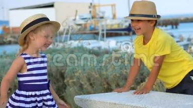 戴帽子的小男孩和小女孩正在游艇码头上玩耍