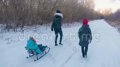 十几岁的女儿和母亲拉着小儿子在雪橇上跑。 剪影一家人在冬天玩。 积极健康