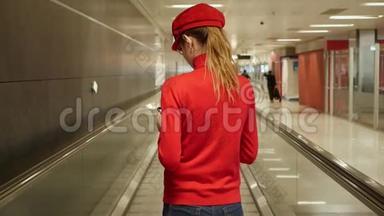 在国际机场的移动通道上带电话的欧洲妇女的后景。 乘客传送带上有智能手机的女孩。