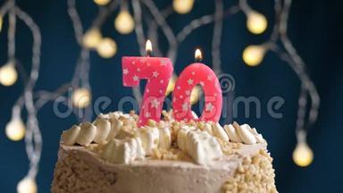 生日蛋糕，70号粉红色燃烧的<strong>蜡烛</strong>在蓝色的背景上。 <strong>蜡烛</strong>吹灭了。 慢速运动和特写镜头