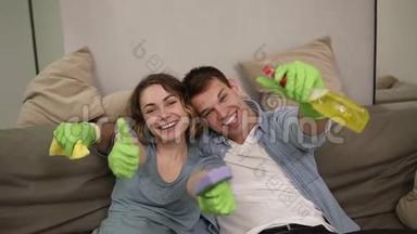 一对年轻快乐的夫妇戴着绿色橡胶手套的肖像。 一家人一起打扫房子。 快乐