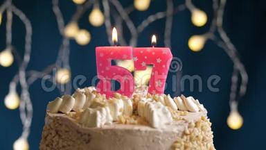 生日蛋糕，上面有57个粉红色的燃烧蜡烛，在蓝色的背景上。 蜡烛吹灭了。 慢<strong>速运</strong>动和特写镜头