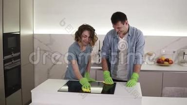 用四只手清洁厨房的烹饪面板。 年轻的男人和女人清理完美的表面