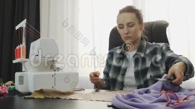 女人在裁缝工作室的桌子上<strong>用布</strong>料和剪刀`工作。 女人做手工服装。 缝纫面料车间。 F
