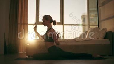 金发白种人的女人在家里练习瑜伽，坐在地板上的黄色垫子上，变换姿势-鸽子姿势-