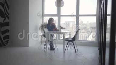 宽镜头优雅的成年白种人妇女坐在桌子上橙汁和水果。 自信的女商人