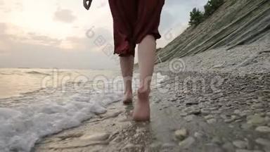 近景后景的双腿白种人女孩<strong>走</strong>在海边的石头海岸的<strong>水中</strong>，<strong>走</strong>向夕阳。