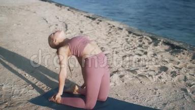 穿<strong>紫色</strong>运动服的女孩在沙滩上练习骆驼<strong>瑜伽</strong>姿势