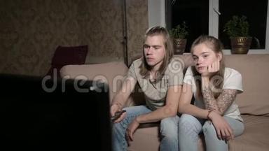 年轻夫妇正在看电视。 人用<strong>遥控器</strong>切换通道.. <strong>特写</strong>