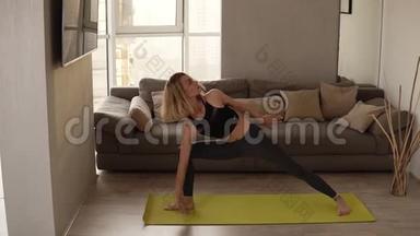 穿着运动服的漂亮女孩在家中练习瑜伽，练习复杂的练习