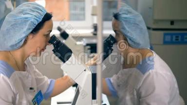 一名医疗技术人员对着显微镜照镜子的脸。