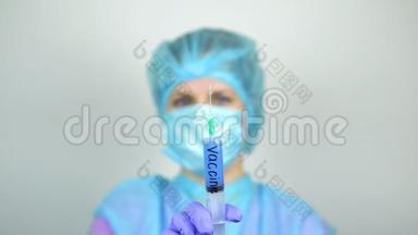 医生，一个女人，手里拿着抗冠状病毒的疫苗，看着它。