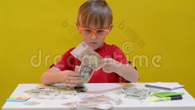 聪明的男孩在桌子上数钱。 孩子为未来的概念省钱