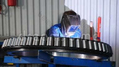 工业工人在轴承厂焊接金属结构。 焊工男工焊接钢结构。 焊工