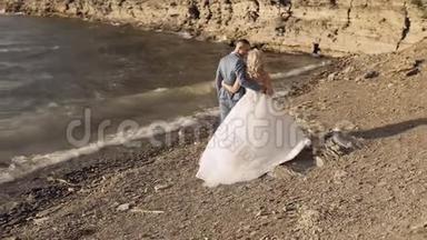 新婚夫妇在河岸上散步。 新娘拥抱新郎。 新婚夫妇
