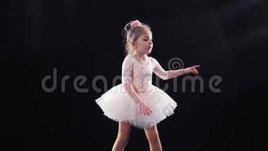 小女孩芭蕾舞演员白种人在舞台上穿着粉红色的芭蕾舞裙跳舞。 孩子们。 慢动作。 对斯泰迪达姆的射击