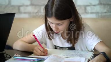聪明的女孩在笔记本上写作，在家学习