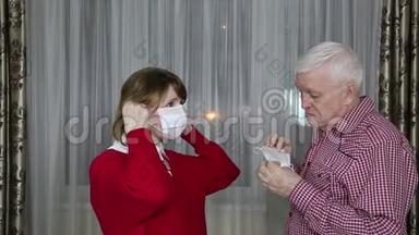 一名中年妇女帮助一名老年男子戴上医疗面罩，以防止病毒感染、流感和结核病。 医药