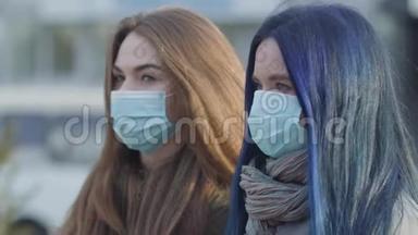侧视特写两个焦虑的女人戴着防护面具看着远处。 站在城市街道上的女人。 重点变化