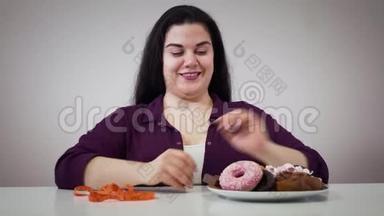 微笑的白人肥胖女孩坐在糖果和测量磁带前的肖像。 一个胖女人把带子挪到一边