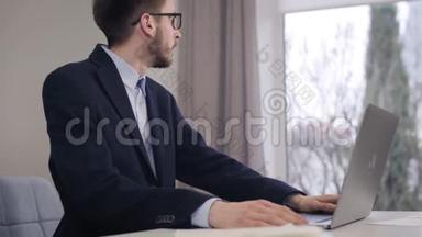 年轻英俊的白种人的肖像，看着窗外，在笔记本电脑键盘上打字。 自信的商人