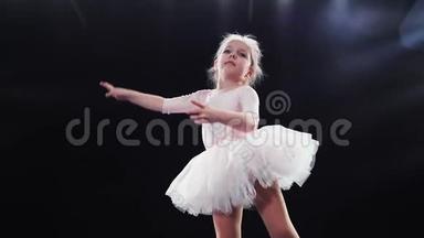 小女孩芭蕾舞演员白种人出现在舞台上，身穿白色芭蕾舞裙。 孩子们。 慢动作