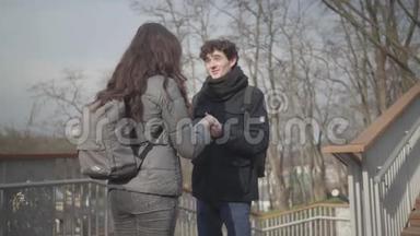 镜头<strong>远离</strong>快乐的年轻白种人男孩与女友在阳光明媚的秋天公园交谈。 快乐的黑发男人