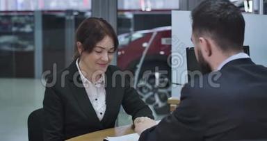 在汽车经销店签署文件的白人女商人的特写。 快乐女车主