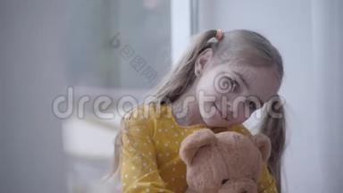 可爱的小女孩的特写肖像，穿着黄色点缀的连衣裙，抱着泰迪熊。 可爱的<strong>白人小孩</strong>抱着玩具