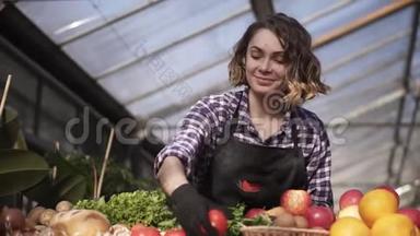 站在农场市场上，戴着黑色手套、摆放有机食品的美丽、微笑的女农低视角