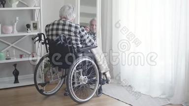 从<strong>轮椅</strong>上成熟的白人男子的背影看镜子里的倒影。 悲伤的<strong>老年</strong>退休人员